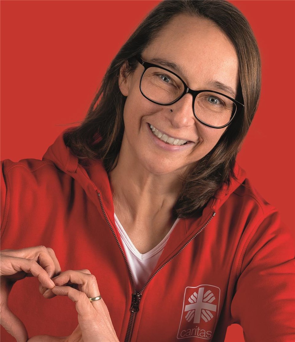 Frau in rotem Hoodie formt mit den Händen ein Herz.
