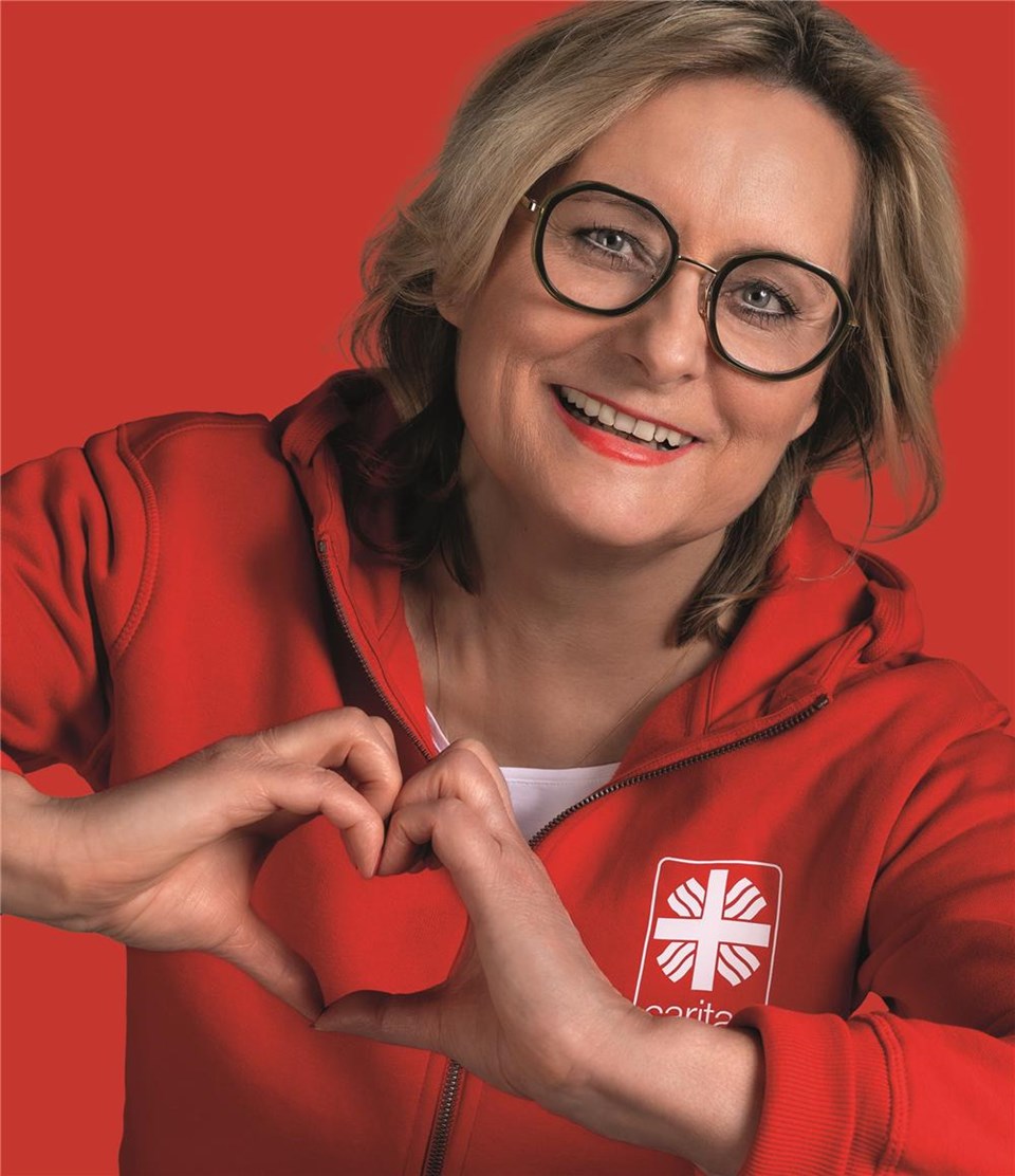 Frau in rotem Hoodie formt mit den Händen ein Herz.