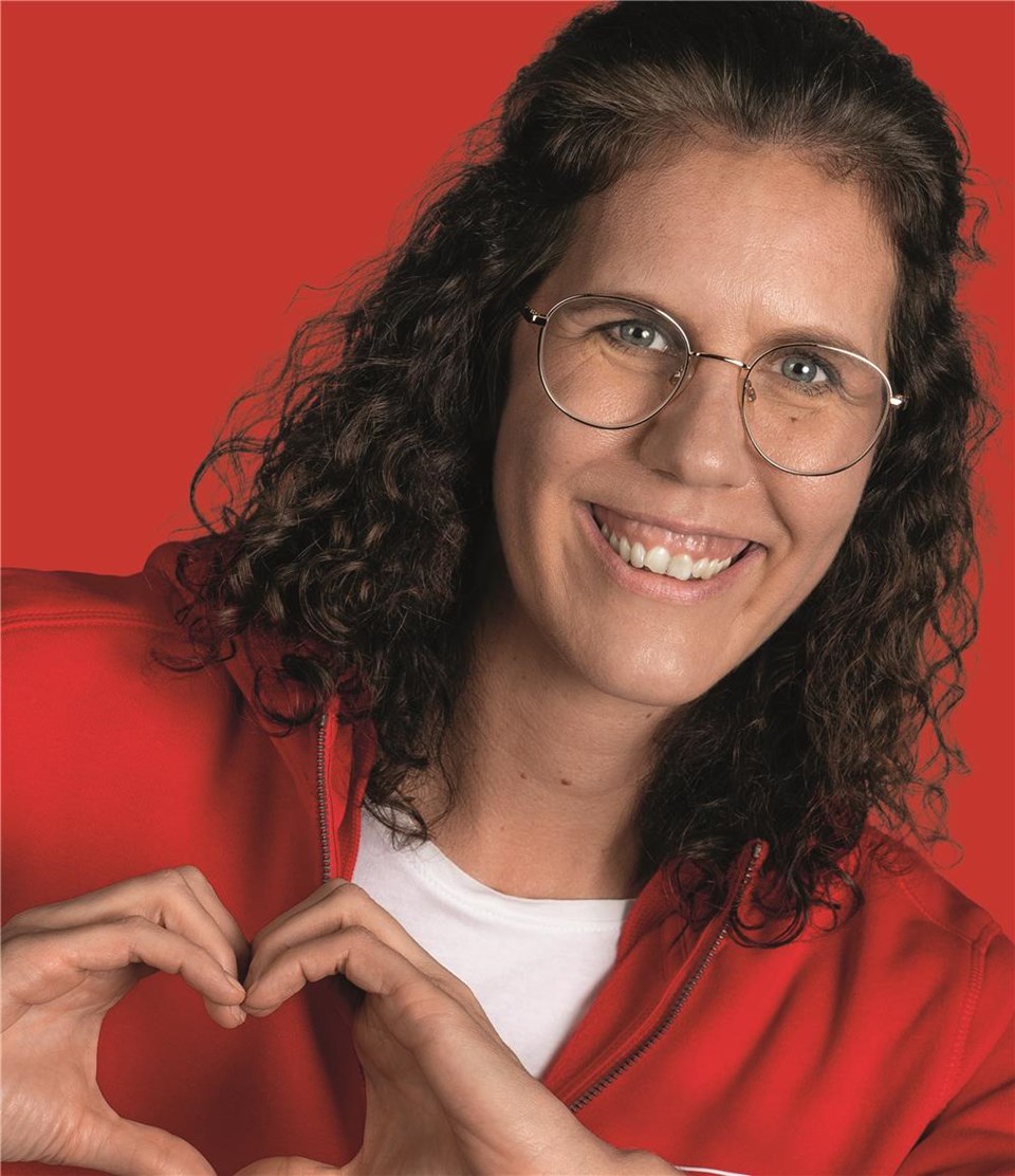 Frau in rotem Hoodie formt mit den Händen ein Herz.