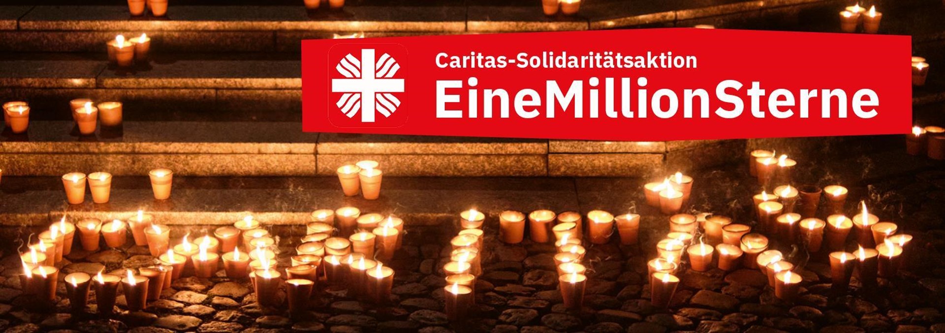 Eine Kerzen Illumination, welche das Wort Caritas darstellt vor einer Treppe im dunklen